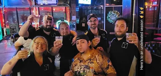 Group of Houston darts community members raising drinks together at a venue