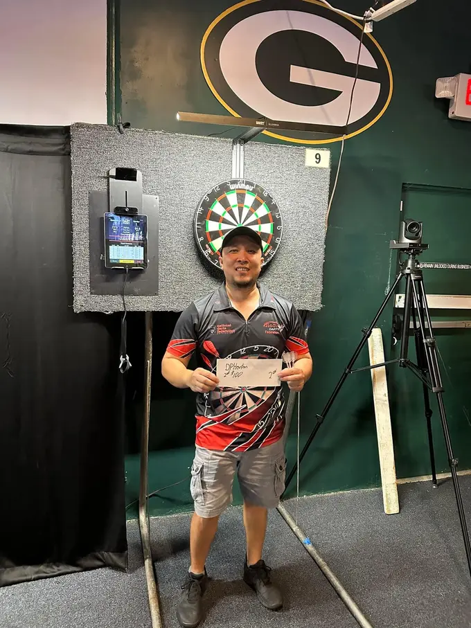 Darts player standing by a board with a keepsake