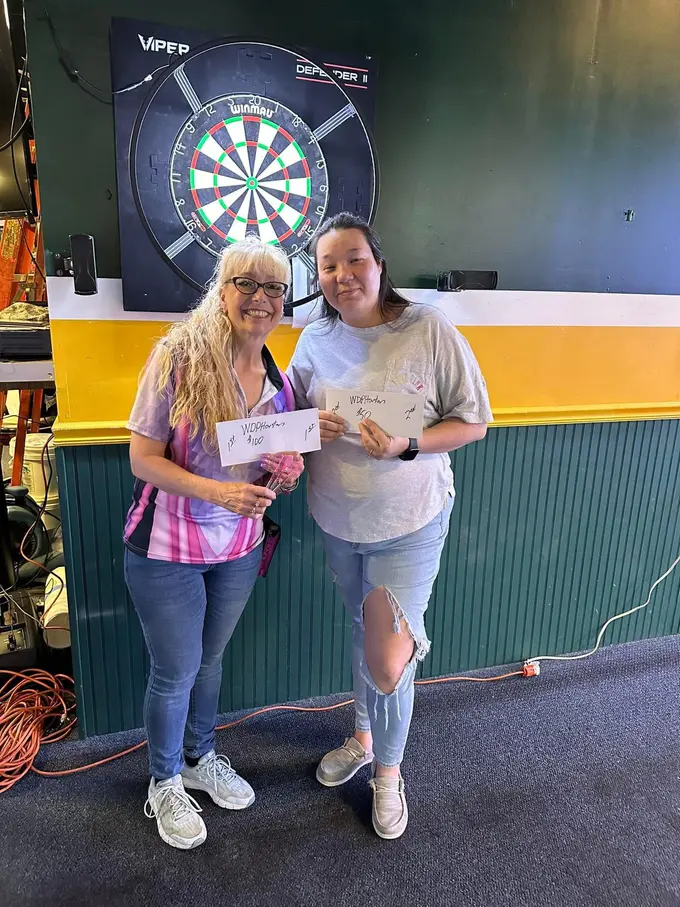 Two people standing together in front of a dartboard