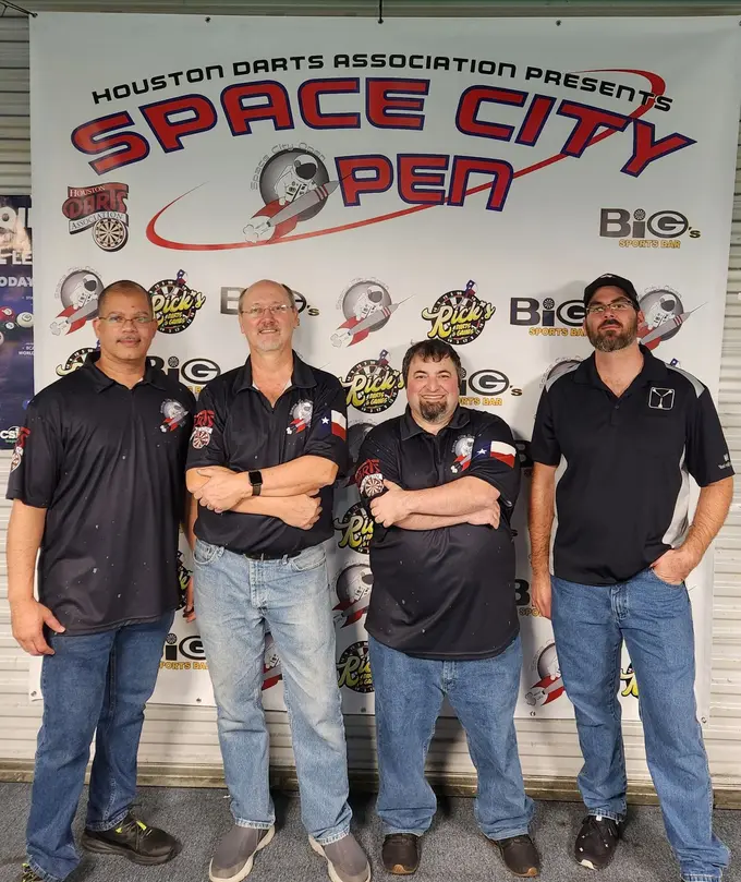 Four darts competitors standing in front of a Space City Open tournament banner