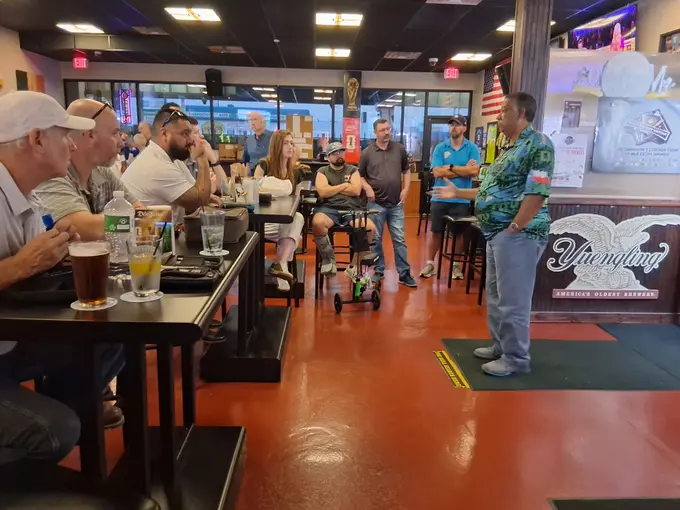 Darts community members seated and standing together during a gathering at a sports bar